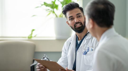 Young doctor speaking with elder patient.